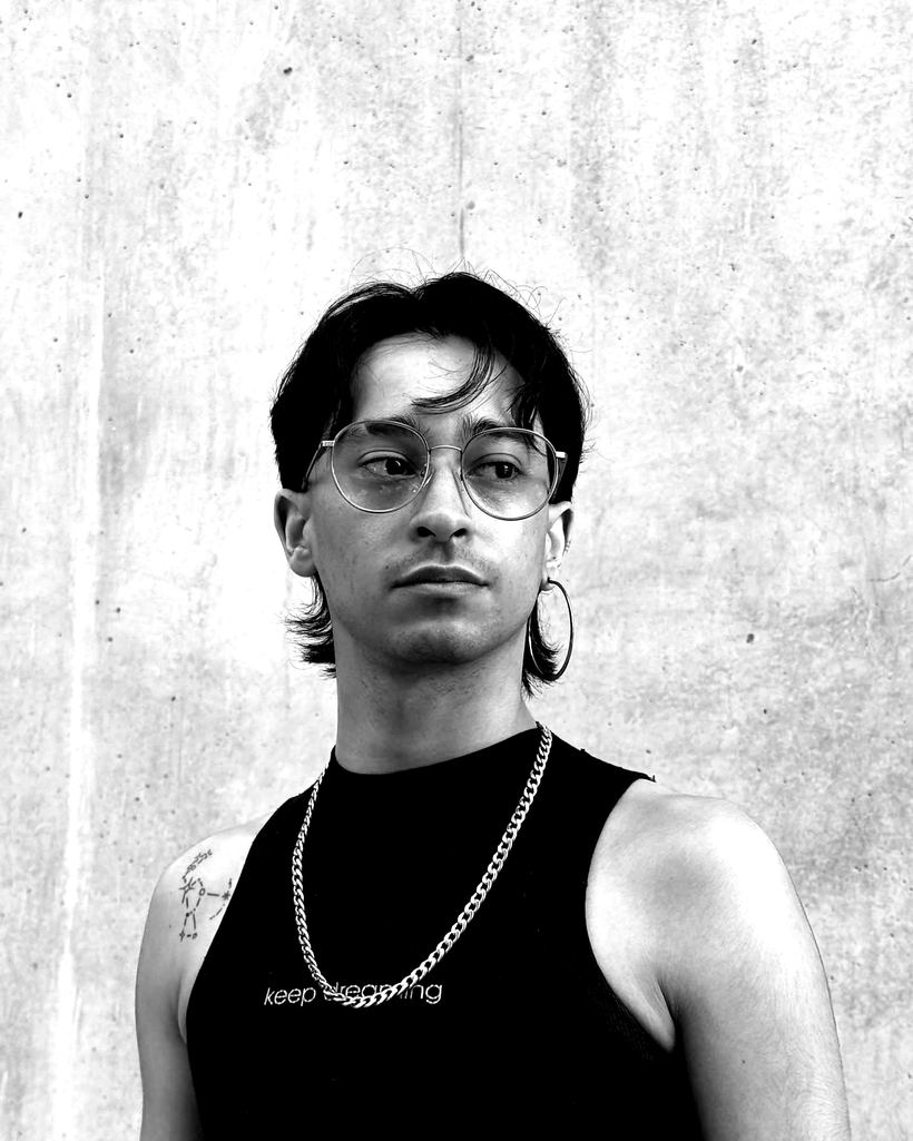 Cliente con mullet y lentes frente a un muro de hormigón